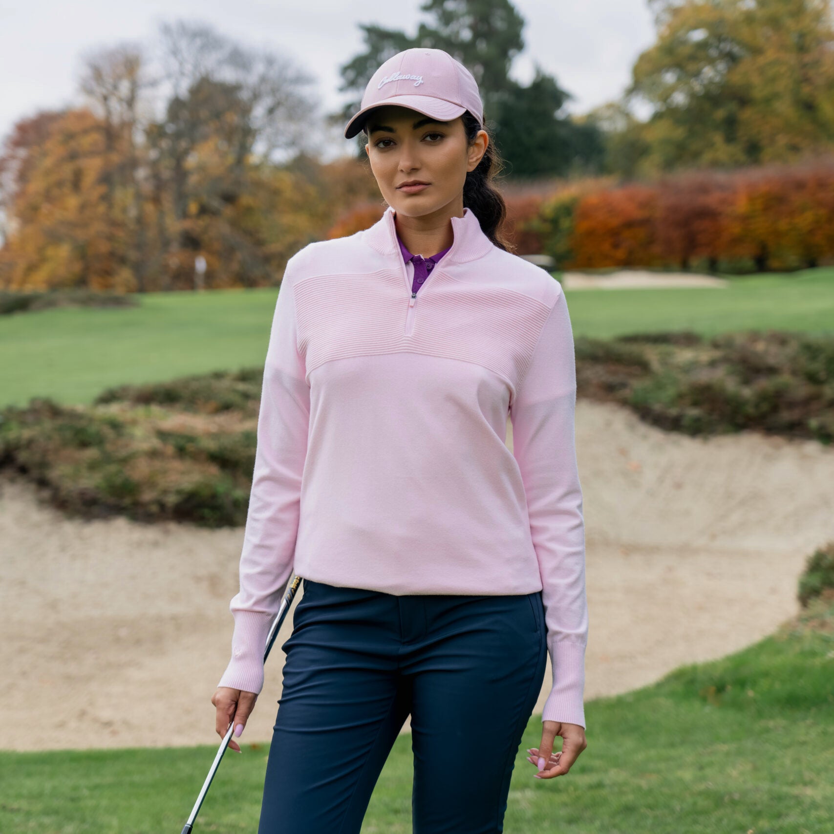 Golfistka v svetri Callaway Soft Stretch Zip-Neck vo farbe čerešňový kvet na golfovom ihrisku