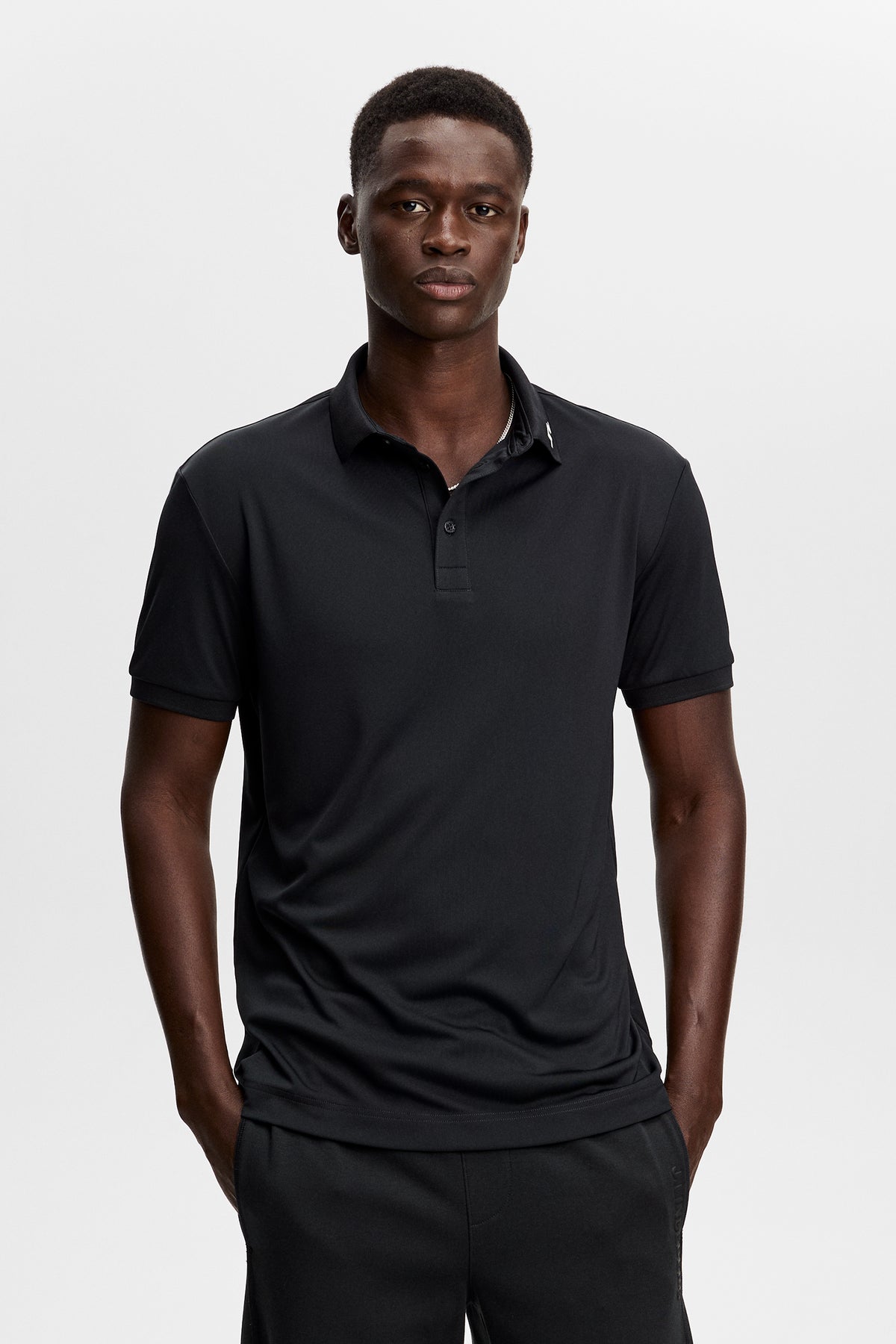 J.Lindeberg KV Print Polo Black – predný pohľad zobrazujúci rebrovaný golier a légu s tromi gombíkmi